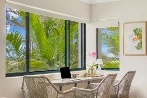 a room with a desk with a laptop in front of windows at Bilinga Bliss - Luxury beachfront apartment in Gold Coast