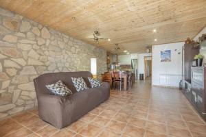 sala de estar con sofá y pared de piedra en El Petit Maialenc, en Mayals