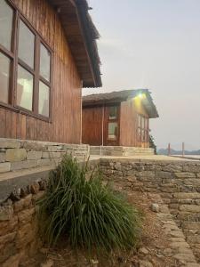 une maison avec un mur en pierre à côté d'un bâtiment dans l'établissement HarroBarro Farms, à Lamjung