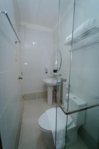a white bathroom with a toilet and a sink at Balay Talisay 