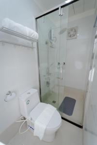 a white bathroom with a shower and a toilet at Balay Talisay 