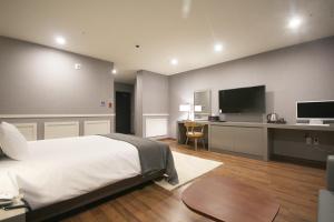 a bedroom with a bed and a desk with a television at Maruo Hotel in Naju