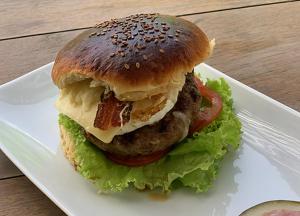 einen Hamburger mit Salat und Tomaten auf einem weißen Teller in der Unterkunft Vila das Águas in Atins