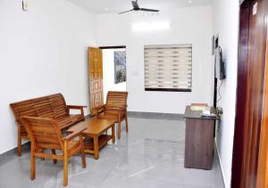 a room with three wooden chairs and a table at Whiteway Homestay in Kūmudi