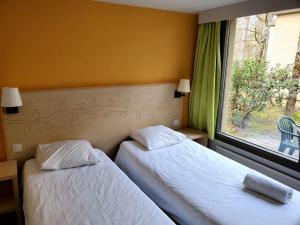 two beds in a hotel room with a window at Cottage-4p-Les Hauts de bruyère-293 in Chaumont-sur-Tharonne