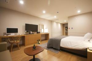 een slaapkamer met een bed en een bureau met een computer bij Maruo Hotel in Naju