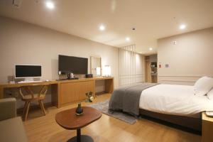 a bedroom with a bed and a desk with a computer at Maruo Hotel in Naju