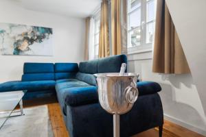 ein Wohnzimmer mit einem blauen Sofa und einem Weinglas in der Unterkunft Traumhaft gelegene Altbau-Wohnung im Herzen von Weinheim in Weinheim