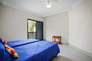 a bedroom with a blue bed and a window at bwelcome - pé na areia com piscina GH in Bertioga +35 photos