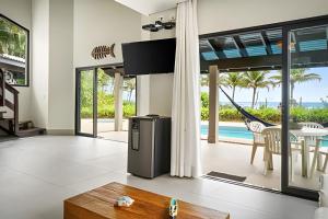 a living room with a tv and a table and a pool at bwelcome - pé na areia com piscina GH in Bertioga