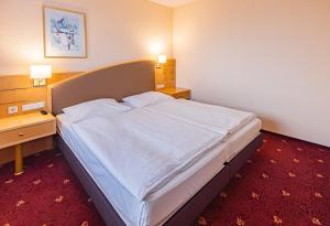 a large bed in a hotel room with two lamps at Ringberg Hotel in Suhl