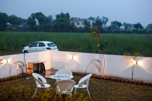 a table and chairs and a white car in a field at Luxuria Farmstays in Jaipur