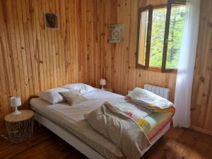 a bed in a wooden room with a window at La Pause Aigoual in Valleraugue