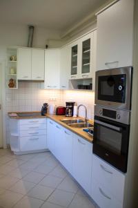 a kitchen with white cabinets and a sink and a microwave at Villa Flora in Kiskunmajsa