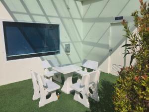 een witte tafel en stoelen in een kamer met een tv bij Angels "Inn" in Phuket