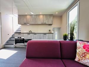 a living room with a purple couch in front of a kitchen at Hausboot Charlottenburg in Zeuthen