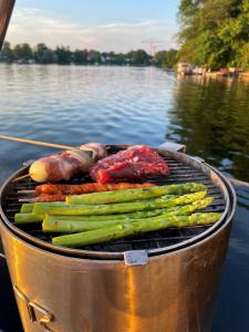 a grill with asparagus and other vegetables on the water at Hausboot Insel Valentinswerder Berlin in Berlin