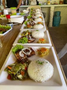 a row of plates of food on a table at Bambua Nature Cottages in Puerto Princesa City