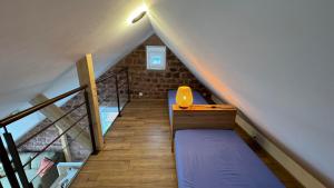 een zolderkamer met een bed en een trap bij Le Pommier - Appt avec jardin partagé in Puberg