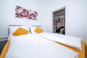 ein weißes Bett mit orangefarbenen und weißen Kissen in der Unterkunft Lipi Apartment in Wien