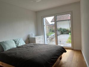 um quarto com uma cama e uma grande janela em Gartenwohnung im modernen Stil em Unterkulm