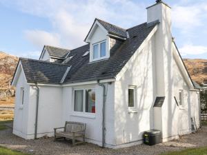 una casa blanca con un banco delante en Viking Cottage, en Lochailort