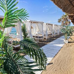 - une rangée de chaises blanches sur la plage dans l'établissement Costalita Apartment - Pool by the Beach, à Estepona