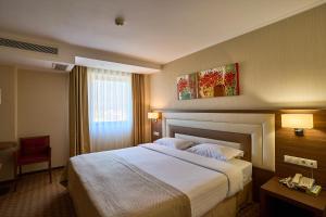 a hotel room with a large bed and a red chair at Central Plaza Hotel in Piatra Neamţ +39 photos