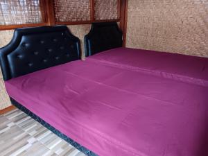 a bed with a pink blanket on top of it at LinkeesHome Bungaya in Karangasem