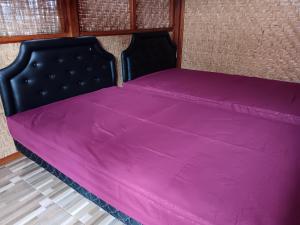 Una cama con una manta rosa encima. en LinkeesHome Bungaya, en Karangasem