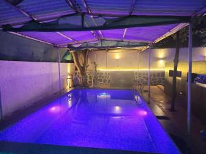 an indoor swimming pool with purple lights in a building at BnBBuddy- Great Escape@Karjat, Maharashtra in Karjat