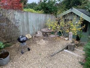 einen Hinterhof mit einem Grill und einem Zaun in der Unterkunft Sweet Modern Country Cottage with Garden in Frome