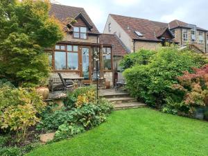 uma casa com um jardim com um pátio e um relvado em Sweet Modern Country Cottage with Garden em Frome