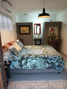 a bedroom with a large bed with a blue flower blanket at Stay @ Dudok in Oudtshoorn