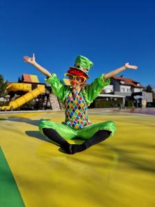 a young boy in a green suit and hat sitting on a playground at Villa Betula Resort & Camping in Žiar