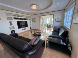 a living room with black leather furniture and a tv at Villa Mafini in Akureyri