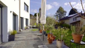 eine Terrasse mit Sonnenschirmen und Topfpflanzen in der Unterkunft Gartenwohnung im modernen Stil in Unterkulm