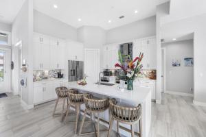 Una cocina con gabinetes blancos y un mostrador con sillas. en 2022 built home with pool/spa and walk to Mackle Park, en Marco Island
