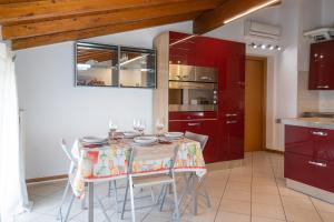 una cocina con armarios rojos y una mesa con sillas. en Incantevole Mansardato 75mq vicino a BGY, en Zanica