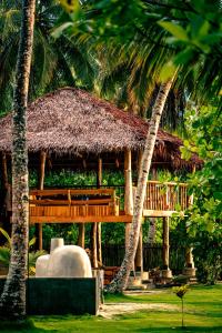 un pavillon en bois avec un toit de paille et des palmiers dans l'établissement Baha Baha Villa Sailo Mentawai, à Katiet