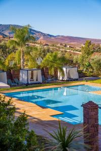 a large swimming pool with tents and palm trees at Kasbah Agounsane in Ourika