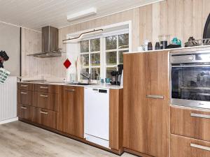 uma cozinha com armários de madeira e uma máquina de lavar louça branca em Apartment Hanstholm em Hanstholm