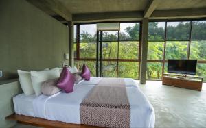 a bedroom with a bed with purple pillows and a television at Wild Grass Nature Resort in Sigiriya