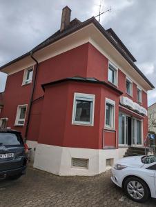 une maison rouge avec des voitures garées devant elle dans l'établissement Ferienwohnung Beck, à Ansbach