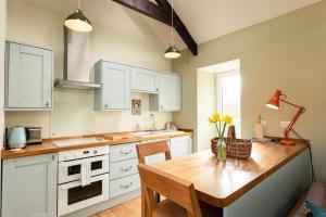 a kitchen with white cabinets and a wooden table at Tranquil 1 bedroom cottage 15 mins drive to sea in Mydroilin