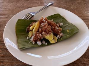 a white plate topped with a green leaf with food on it at LinkeesHome Bungaya in Karangasem