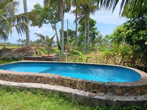 una grande piscina con un muro di pietra intorno di LinkeesHome Bungaya a Karangasem