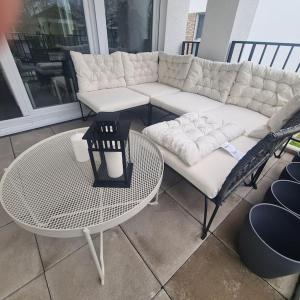 ein weißes Sofa und einen Tisch auf der Terrasse in der Unterkunft bookandstay24 Hanau Ferienwohnung mit Küche, Balkon und Parkplatz in Hanau am Main