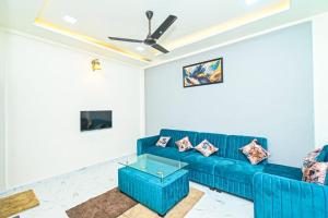 um sofá azul numa sala de estar com uma ventoinha de tecto em SK Villa em Āmbavna