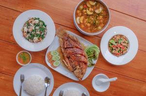 una mesa con platos de comida y tazones de comida en BaanRai KhunYa บ้านไร่คุณย่า, en Sai Yok